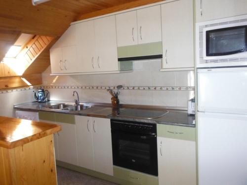 a kitchen with white cabinets and a sink and a refrigerator at Apartamentos Casa Borja in Salinas de Bielsa