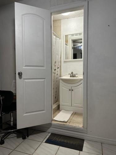 een witte badkamer met een wastafel en een spiegel bij COZY QUEEN BED STUDIO NEAR DOLPHIN MALL-FIU in Miami