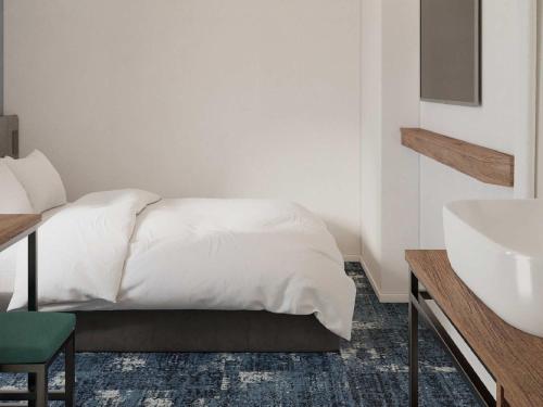 a bedroom with a white bed and a sink at Prince Smart Inn Miyazaki in Miyazaki