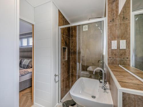 a white bathroom with a sink and a shower at Billy Goat Lodge in Crossway Green