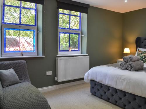 a bedroom with a bed and two windows and a chair at Chapel Lodge in Hornsea