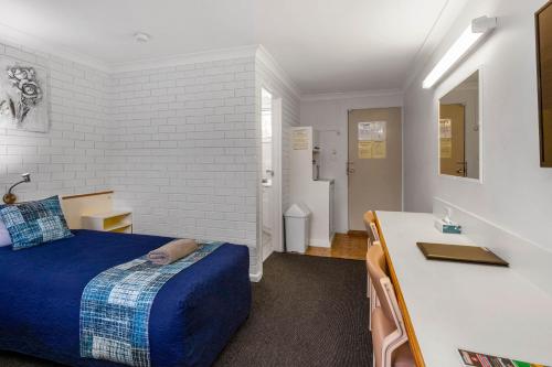 a bedroom with a bed and a desk and a sink at Leichhardt Motor Inn in Toowoomba