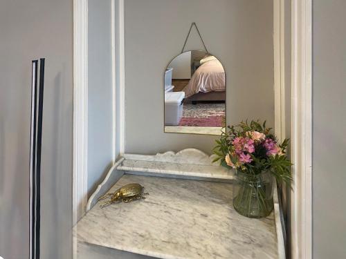 a bathroom with a mirror and a vase of flowers on a counter at Frankfurt Flat - Uk44457 in Two Dales