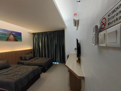um quarto de hotel com duas camas e uma televisão em Hanan Studio Apartment with Pool, Wifi & Netflix em Gua Musang