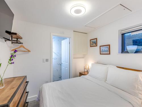 a white bedroom with a bed and a window at Wharf Annex in Coombe Hill