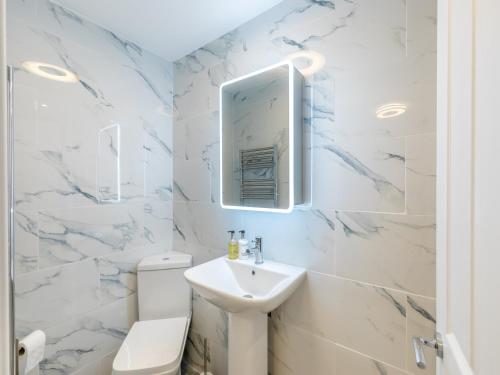 a white bathroom with a sink and a toilet at Wharf Annex in Coombe Hill