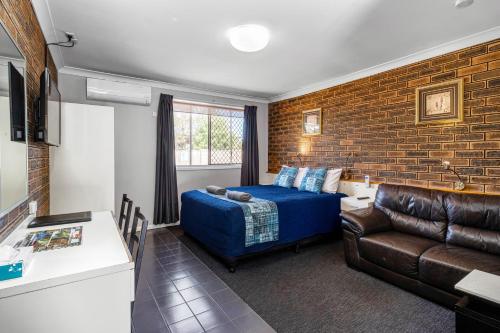 a bedroom with a bed and a couch and a brick wall at Leichhardt Motor Inn in Toowoomba