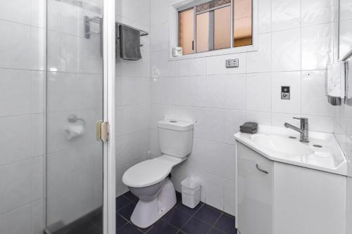 a white bathroom with a toilet and a sink at Leichhardt Motor Inn in Toowoomba