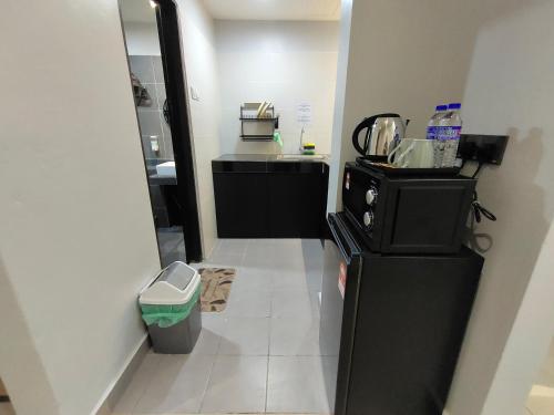 uma cozinha com um frigorífico preto e piso em azulejo branco em Hanan Studio Apartment with Pool, Wifi & Netflix em Gua Musang