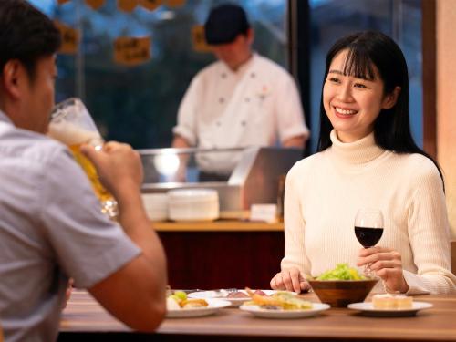 uma mulher sentada à mesa com um copo de vinho em Hotel Ichinose em Yamanouchi