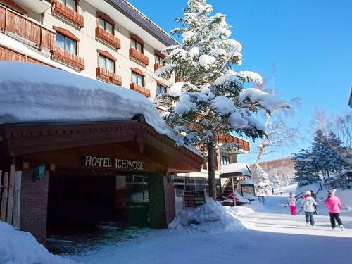 a hotel with a snow covered tree next to a building at Hotel Ichinose in Yamanouchi