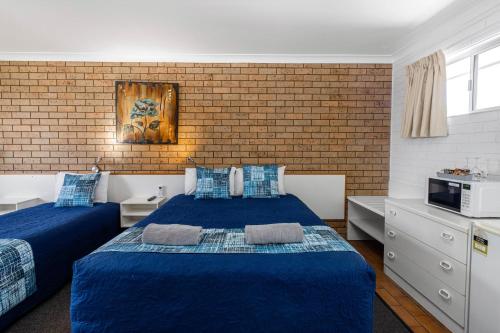 a bedroom with two beds and a brick wall at Leichhardt Motor Inn in Toowoomba