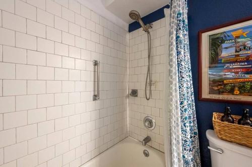 a white tiled bathroom with a shower and a tub at Kihei Alii Kai D207- Ocean view, walk to shops, dining, and Kam I Beach in Kihei