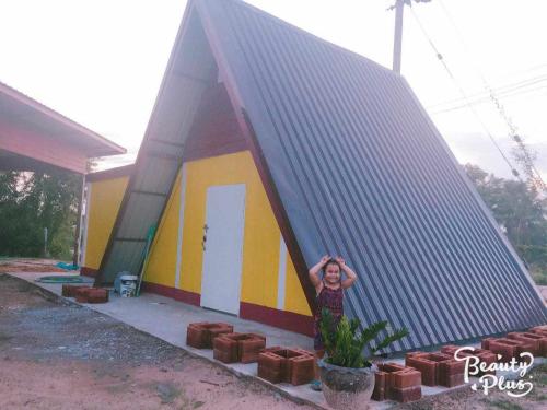 una mujer parada frente a una casa pequeña en นามนโฮมสเตย์ (บ้านพ่อเสถียร) 