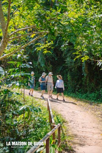 a group of people walking down a dirt trail at La Maison De Buoc in Mai Chau