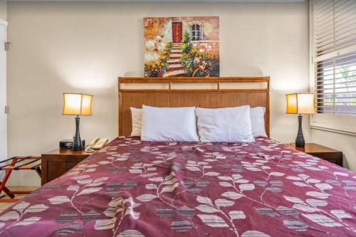 ein Schlafzimmer mit einem Bett, zwei Lampen und einem Gemälde in der Unterkunft Kamaole Sands 2-306- Kamaole Sands spacious, updated, and Oceanview! in Wailea