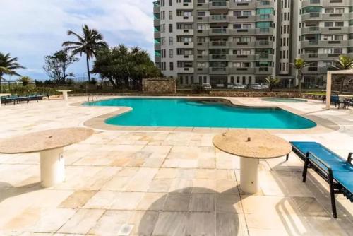 una piscina con 2 mesas y un edificio en Apartamento Sun Barra Tijuca frente Mar, en Río de Janeiro