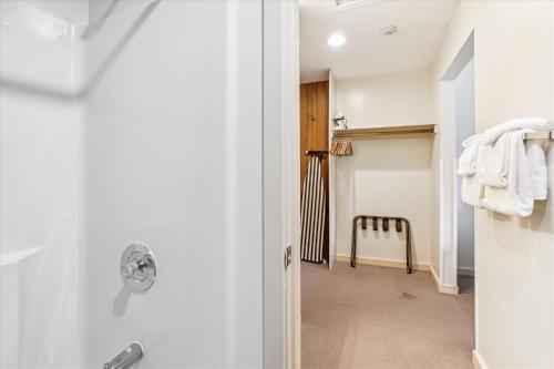 baño con puerta blanca y silla en Cedarbrook Two Double bed Standard Hotel room 219, en Killington