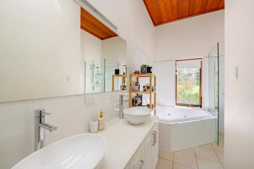 a white bathroom with two sinks and a tub at Amongst the Vines Deluxe Retreat in Blewitts Springs