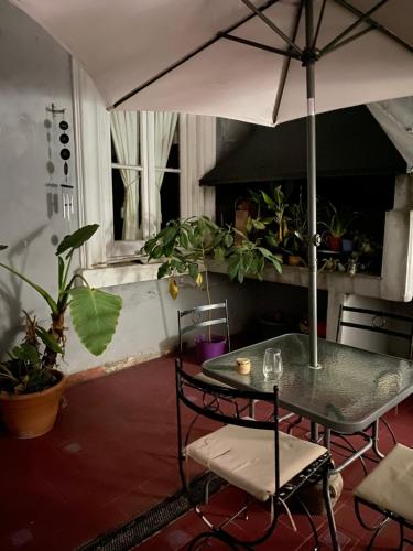a table and chairs with an umbrella in a room at Rivière Hostel in Cordoba