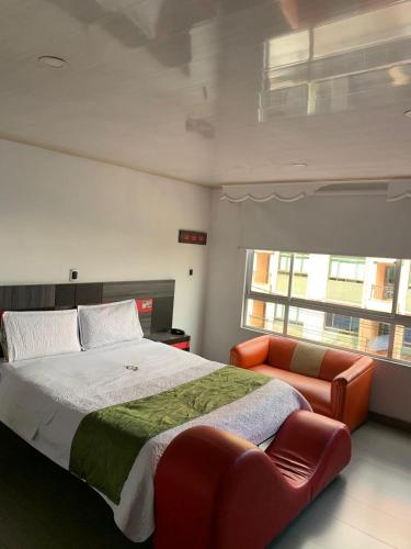 ein Schlafzimmer mit einem großen Bett und einer orangefarbenen Couch in der Unterkunft Hotel Planeta 3 in Bogotá