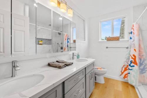 a white bathroom with two sinks and a toilet at Shark's Cove Front, Sea View, Large 2BR, Full Kitchen, contact us for price drop in Haleiwa