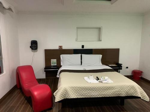 a bedroom with a bed and a red chair at Hotel Planeta 3 in Bogotá