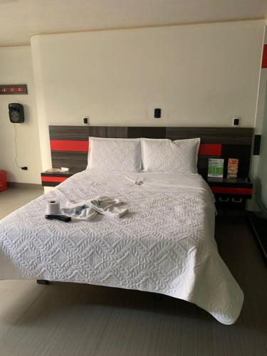 a white bed with a pair of shoes on it at Hotel Planeta 3 in Bogotá