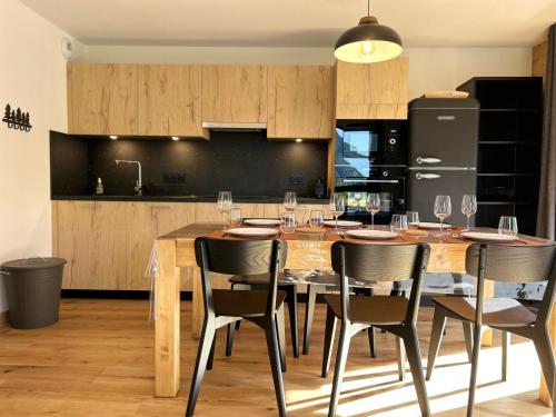 - une cuisine avec une table en bois, des chaises et des verres à vin dans l'établissement Appartement neuf aux Gets, proche remontées mécaniques, terrasse sud, 6 couchages, garage, WiFi - FR-1-623-350, aux Gets