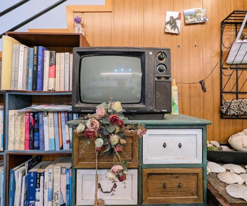 uma velha televisão sentada numa mesa em frente a uma estante de livros em Meow! Marcia Youth Hostel em Pingtan