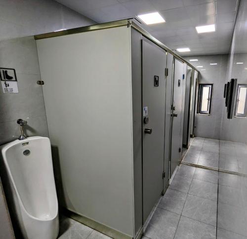 a row of stalls in a bathroom with a urinal at Meow! Marcia Youth Hostel in Pingtan