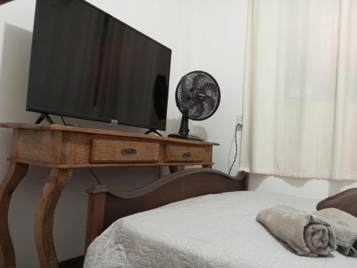 a television on a table with a bed and a fan at Mini Casa Furnas - Capitólio MG in São José da Barra