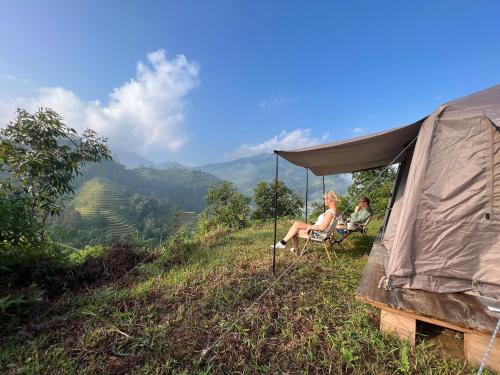 2 personnes assises dans une tente au sommet d'une colline dans l'établissement Nậm Lỳ Retreat- Breakfast included, à Ha Giang