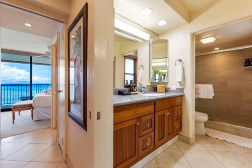 a bathroom with a sink and a toilet and a mirror at Hololani A404- Ocean views from every room, 2 bedroom condo in Kahana