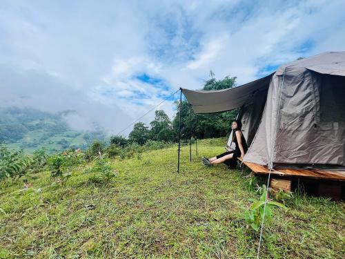 a woman sitting in front of a tent on a hill at Nậm Lỳ Retreat in Ha Giang