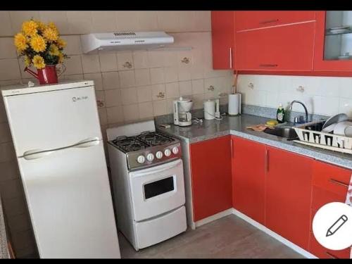 a kitchen with a white stove and red cabinets at Espacioso departamento in Lima