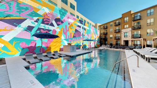 a pool with chairs and a wall with a mural at Modern comfort at The Domain Austin ,Texas in Austin