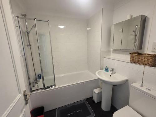 a white bathroom with a sink and a shower at Entire South London Apartment hosted by Pius in Croydon