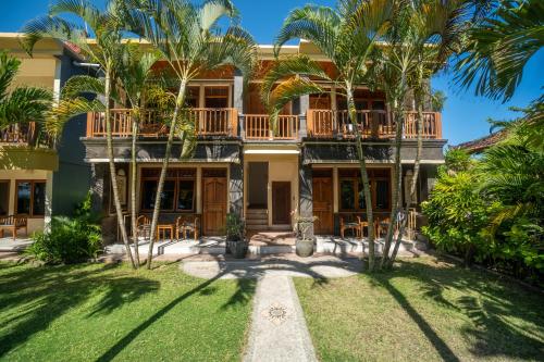 a house with palm trees in front of it at Kembang Kuning in Uluwatu