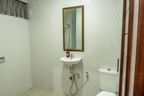a bathroom with a sink and a toilet and a mirror at Maharani Hostel in Ubud