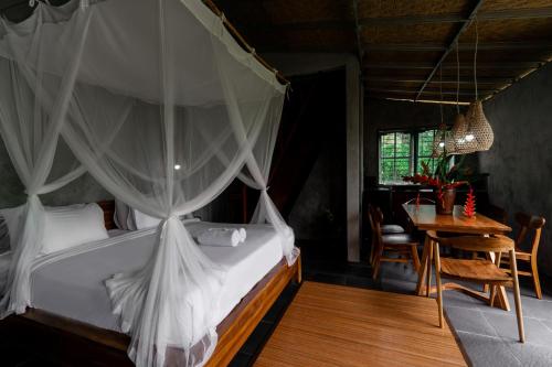 a bedroom with a canopy bed and a table at Padangan Lodge By Bali Cabin in Padangan