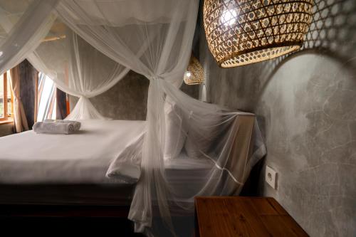 a bedroom with a bed with curtains and a chandelier at Padangan Lodge By Bali Cabin in Padangan
