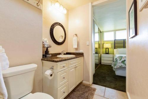 a bathroom with a sink and a toilet and a mirror at Hale Ono Loa 114- Ground floor partial ocean view gem in Kahana
