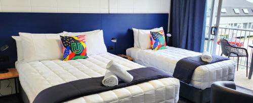 two beds in a room with blue walls at Urban Lounge Sleepery in Rotorua
