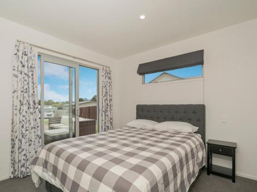 a bedroom with a bed and a large window at A Sunshine Retreat - Pauanui Holiday Home in Pauanui
