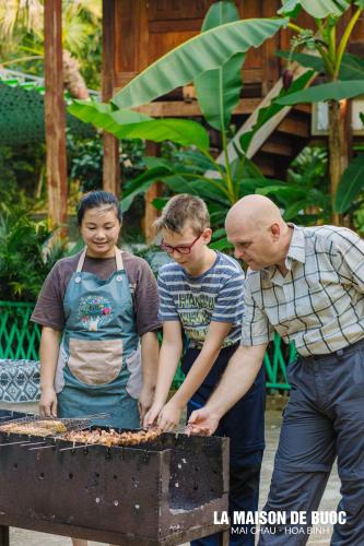 a group of people standing around a barbecue grill at La Maison De Buoc in Mai Chau