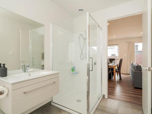 a white bathroom with a shower and a sink at A Sunshine Retreat - Pauanui Holiday Home in Pauanui