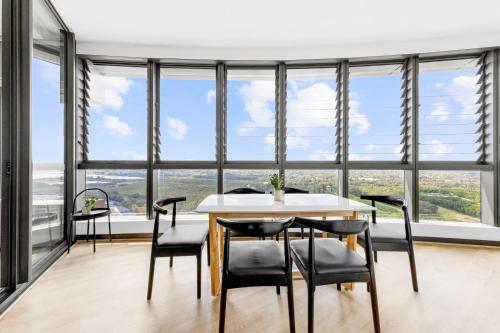 uma sala de jantar com mesa e cadeiras e janelas grandes em Amazing city view high level Apt em Sydney