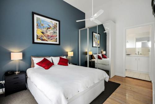 een slaapkamer met een groot wit bed met rode kussens bij Fantastic Beachside Townhouse in Victor Harbor