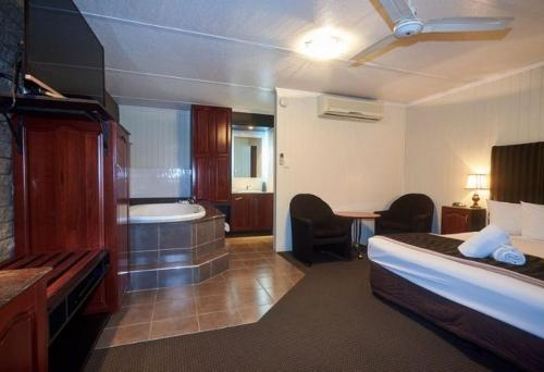 Habitación de hotel con cama y bañera en Country Plaza Motor Inn, en Mackay